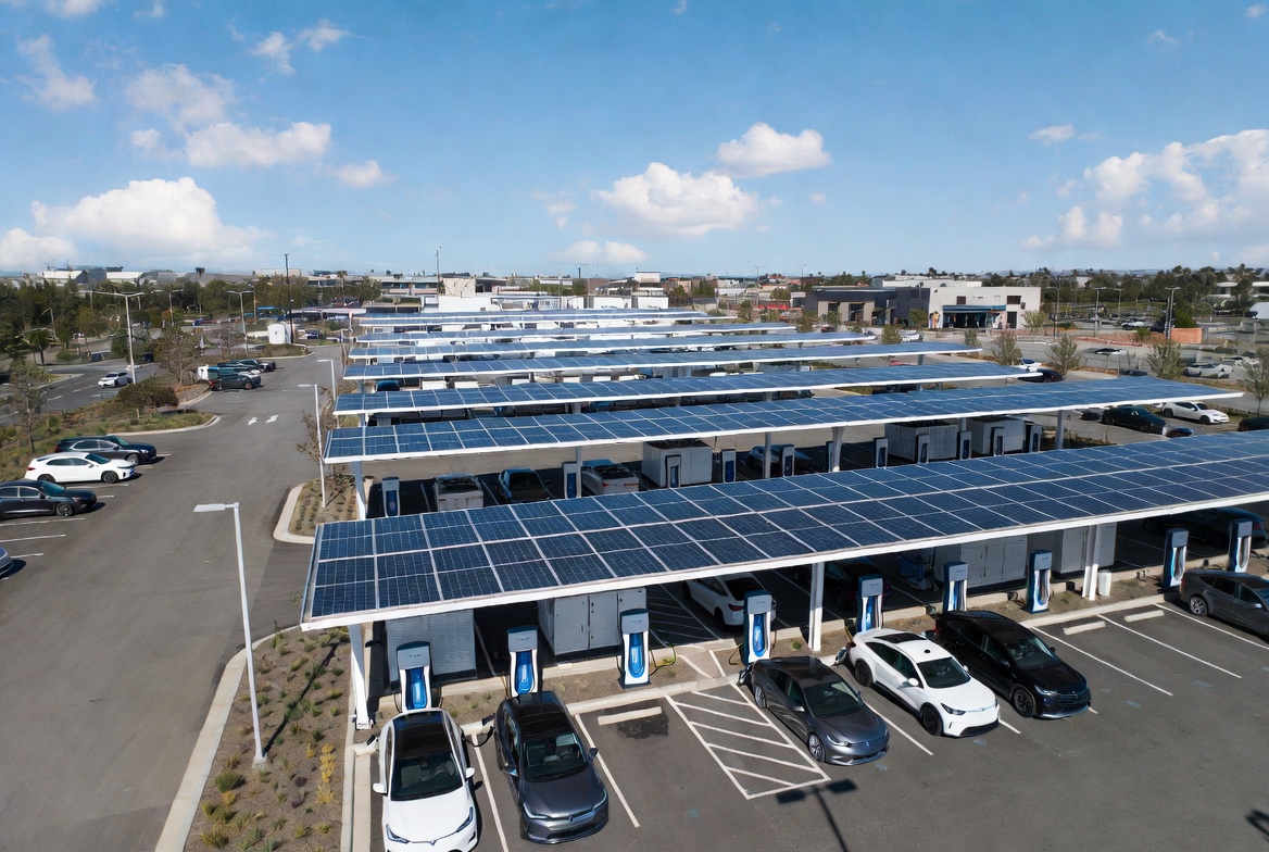 Large-scale solar canopy EV charging plaza with rows of solar panels over parking spaces, DC fast chargers, and electric vehicles — the exact vision Vats Brothers brings to Calgary commercial properties